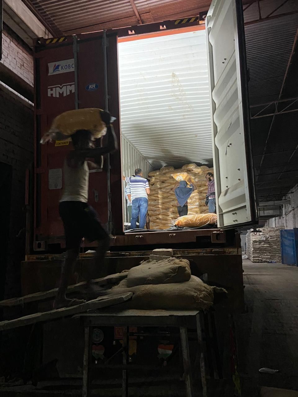 Workers loading bags of rice into a container
